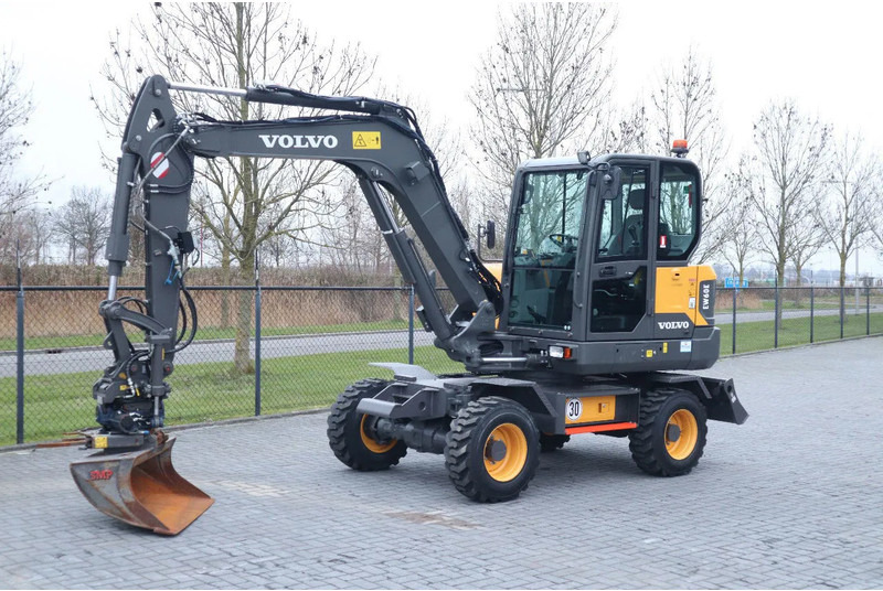 Volvo EW60E | DEMO | 30 KM/H | ROTOTILT + GRIPPER | BUCKET - Gumikerekes kotró: 2 kép. Volvo EW60E | DEMO | 30 KM/H | ROTOTILT + GRIPPER | BUCKET - Gumikerekes kotró: 2 kép.