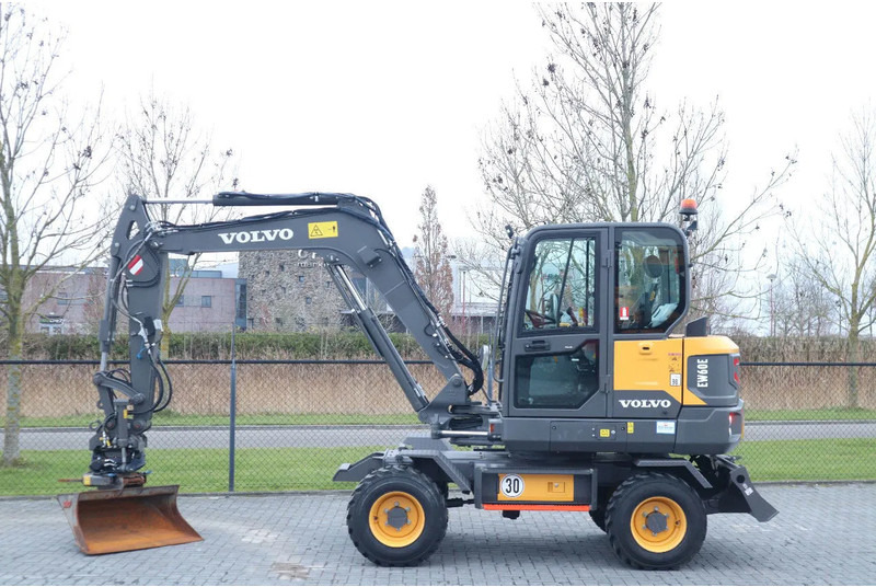 Volvo EW60E | DEMO | 30 KM/H | ROTOTILT + GRIPPER | BUCKET - Gumikerekes kotró: 1 kép. Volvo EW60E | DEMO | 30 KM/H | ROTOTILT + GRIPPER | BUCKET - Gumikerekes kotró: 1 kép.