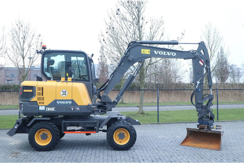 Volvo EW60E | DEMO | 30 KM/H | ROTOTILT + GRIPPER | BUCKET - Gumikerekes kotró: 4 kép. Volvo EW60E | DEMO | 30 KM/H | ROTOTILT + GRIPPER | BUCKET - Gumikerekes kotró: 4 kép.