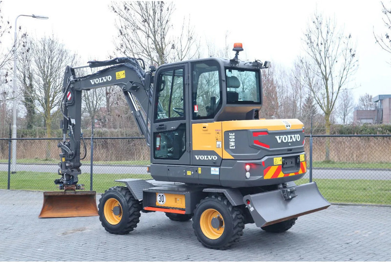 Volvo EW60E | DEMO | 30 KM/H | ROTOTILT + GRIPPER | BUCKET - Gumikerekes kotró: 3 kép. Volvo EW60E | DEMO | 30 KM/H | ROTOTILT + GRIPPER | BUCKET - Gumikerekes kotró: 3 kép.