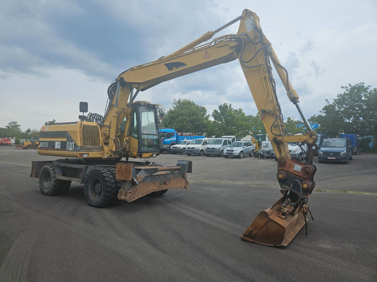 CAT M315 Mobilbagger mit Pratzen und Schild - Gumikerekes kotró: 4 kép. CAT M315 Mobilbagger mit Pratzen und Schild - Gumikerekes kotró: 4 kép.