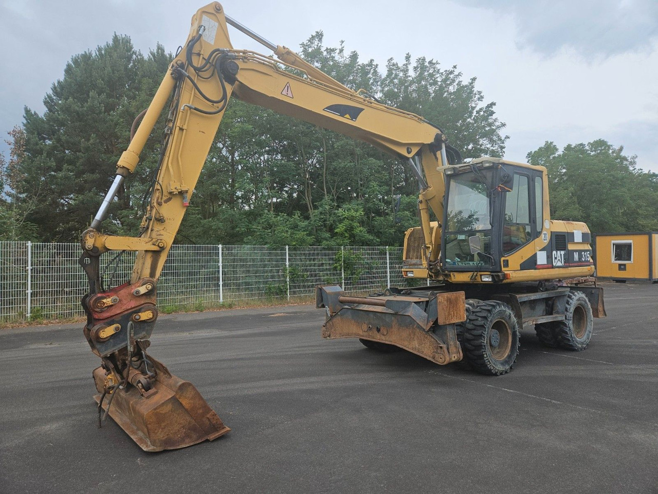 CAT M315 Mobilbagger mit Pratzen und Schild - Gumikerekes kotró: 1 kép. CAT M315 Mobilbagger mit Pratzen und Schild - Gumikerekes kotró: 1 kép.