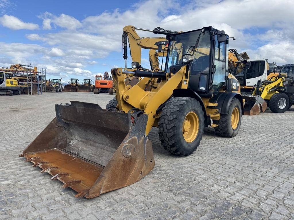 CAT 908M mit Klappschaufe und Palletengabeln - Gumikerekes homlokrakodó: 1 kép. CAT 908M mit Klappschaufe und Palletengabeln - Gumikerekes homlokrakodó: 1 kép.