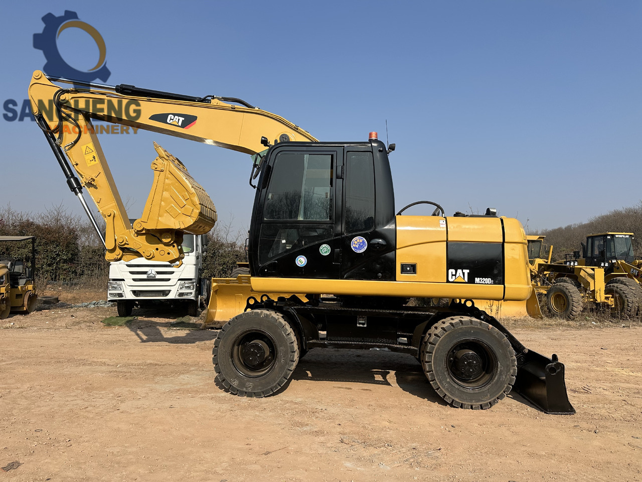 CATERPILLAR M320D2 - Gumikerekes kotró: 1 kép. CATERPILLAR M320D2 - Gumikerekes kotró: 1 kép.